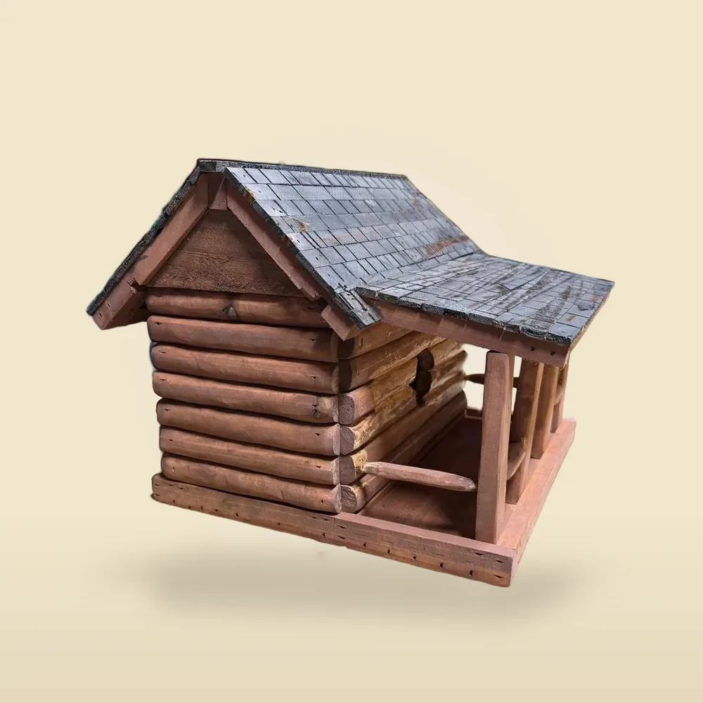 Log-cabin birdhouse with a hand-shingled roof and a covered porch