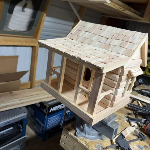 A log cabin birdhouse from the front, porch posts and rail in place