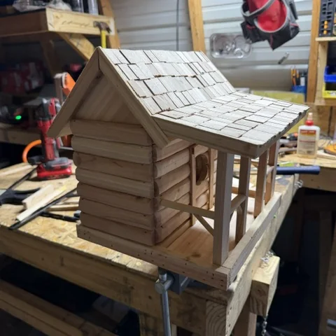 The cabin birdhouse side on, showing the stacked log walls