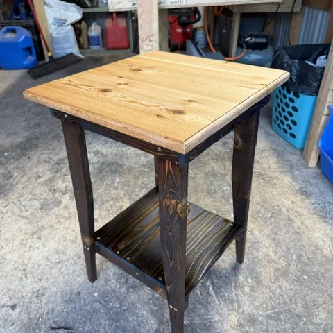 A side table finished with dark torched legs beneath a natural top