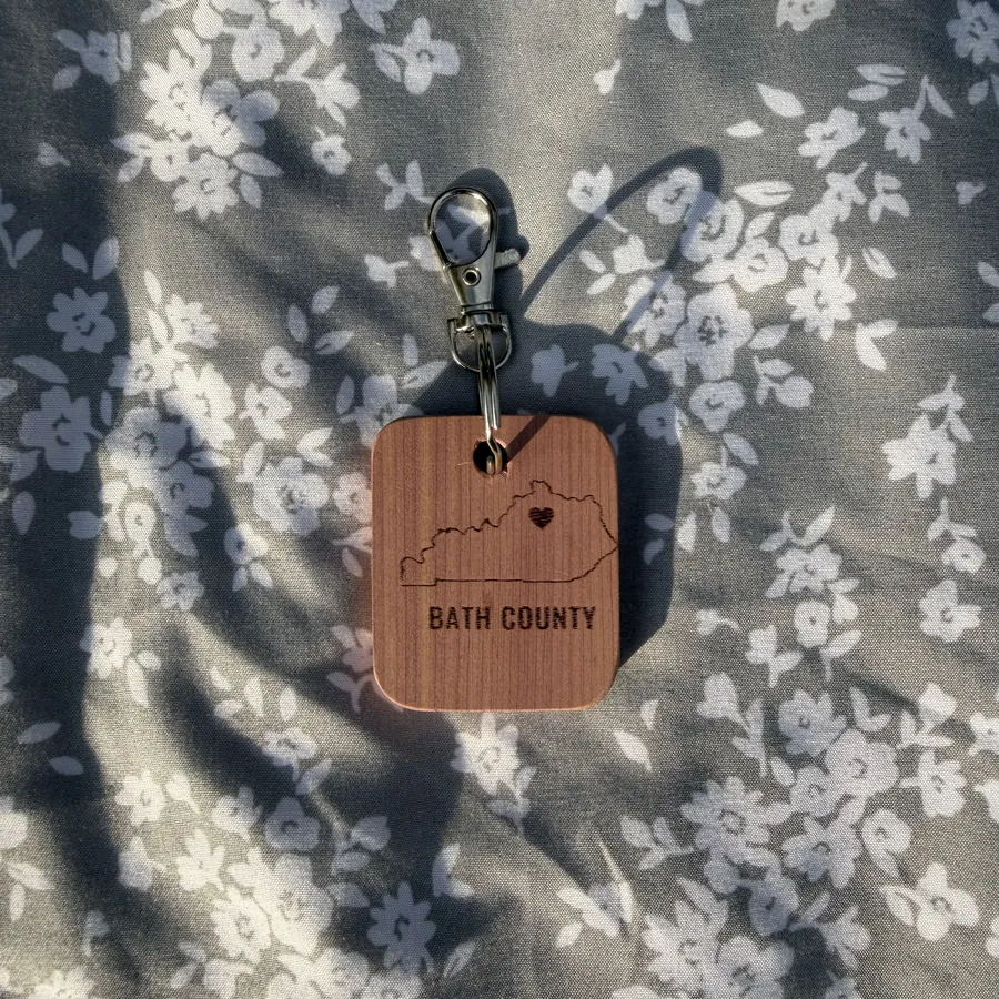 Solid red cedar keychain with a burned-in design, split ring and swivel clasp
