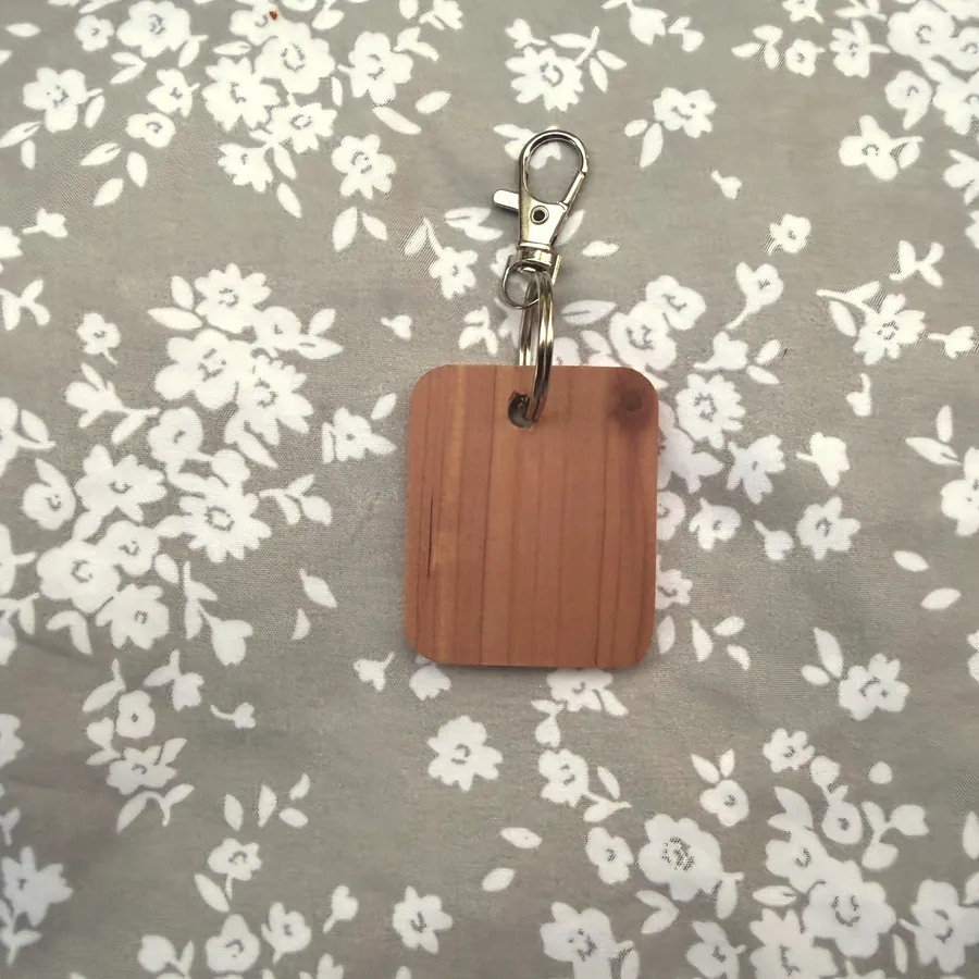 Bare red cedar keychain blank with a split ring and swivel clasp, before engraving
