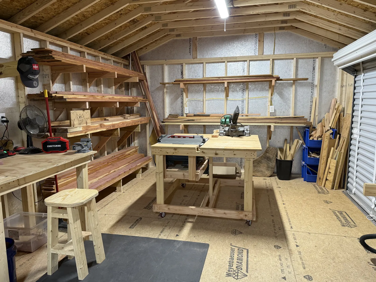 The lumber wall in Harley's rebuilt shop: racks of red cedar boards over the rolling saw bench